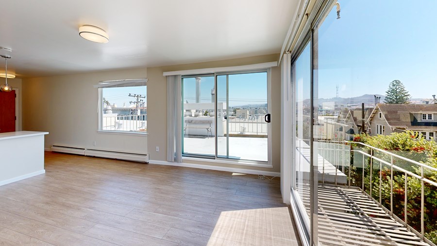 A spacious room with a balcony overlooking a residential area.